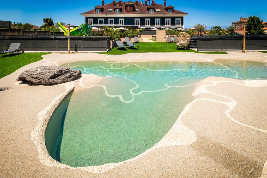 Piscina de arena con forma orgánica y el edificio al fondo