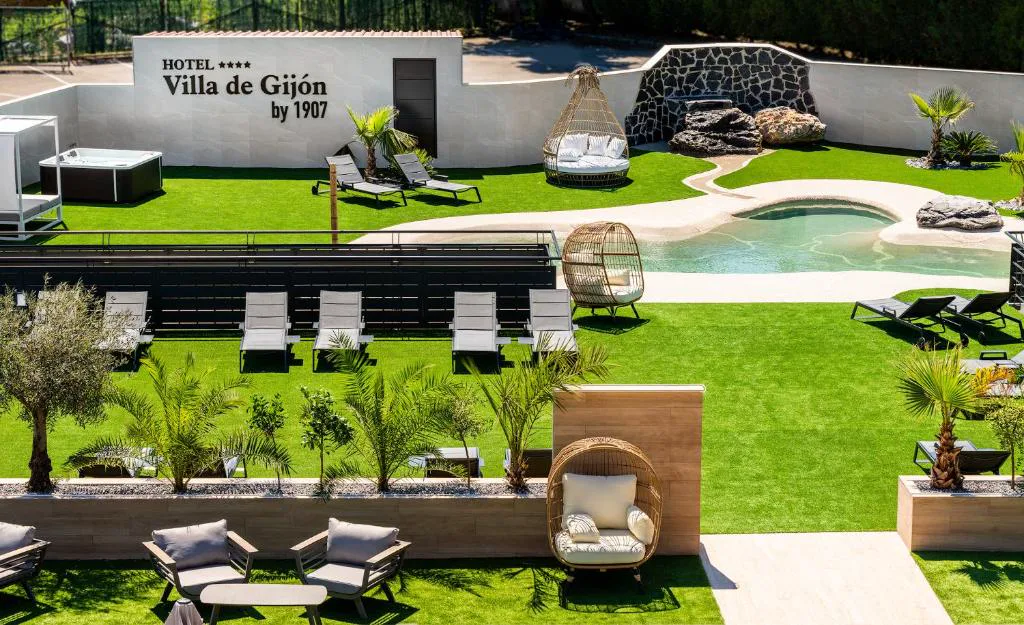 Jardín con piscina, hamacas y cartel de Villa de Gijón