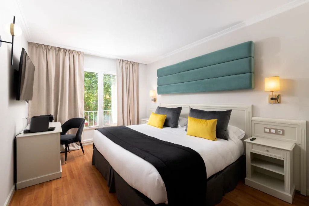 Habitación con cabecero verde, cama doble y escritorio