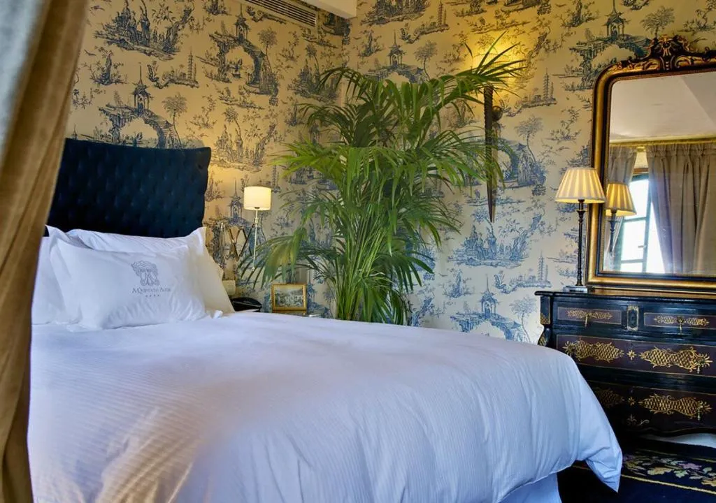 Dormitorio con papel pintado chinoiserie en azul y blanco, cabecero de terciopelo negro y tocador de época