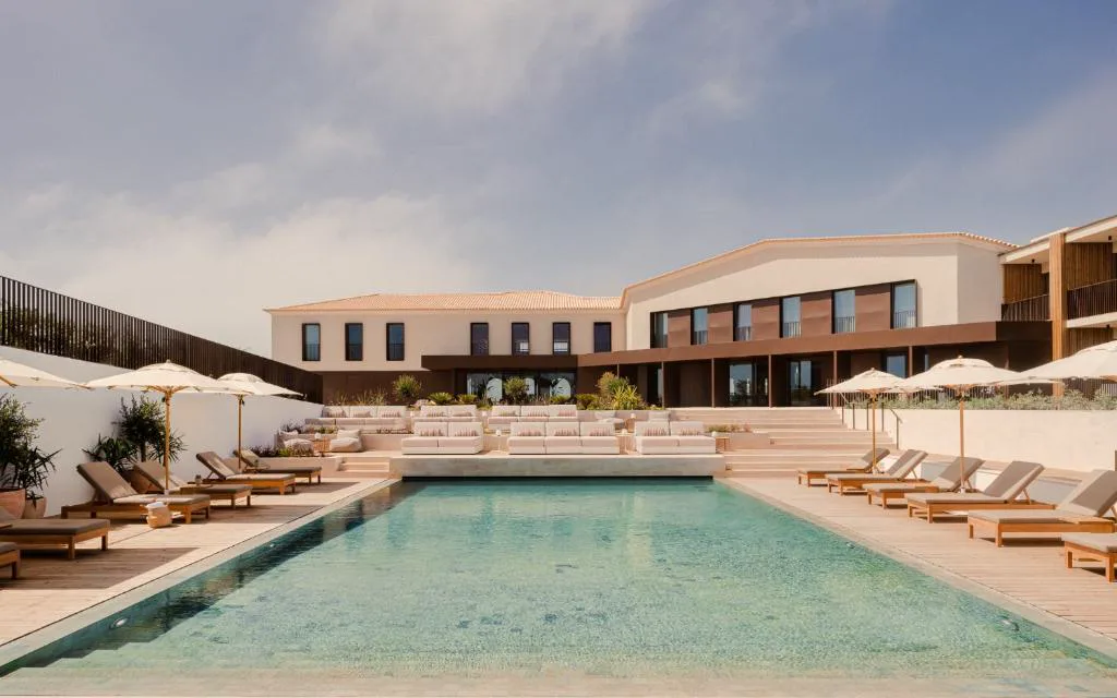 Piscina exterior de Aethos Hotel Ericeira con tumbonas y vistas al edificio principal