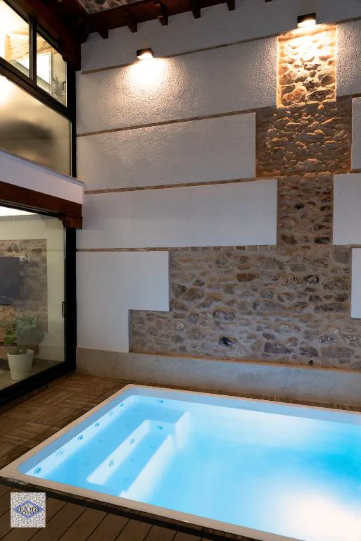 Piscina pequeña con escalón de madera en un patio de piedra