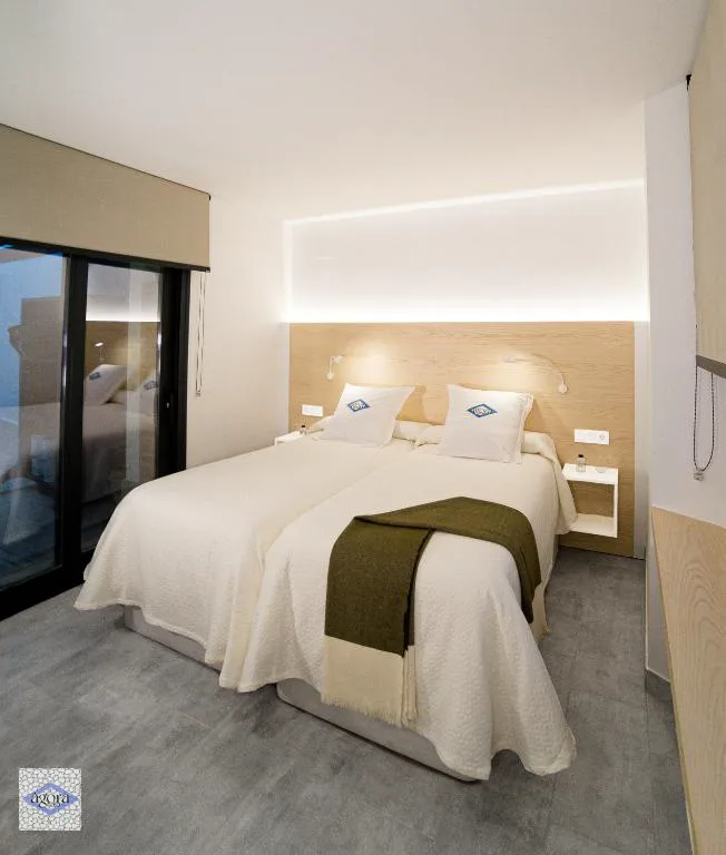 Habitación con cama blanca y mesitas