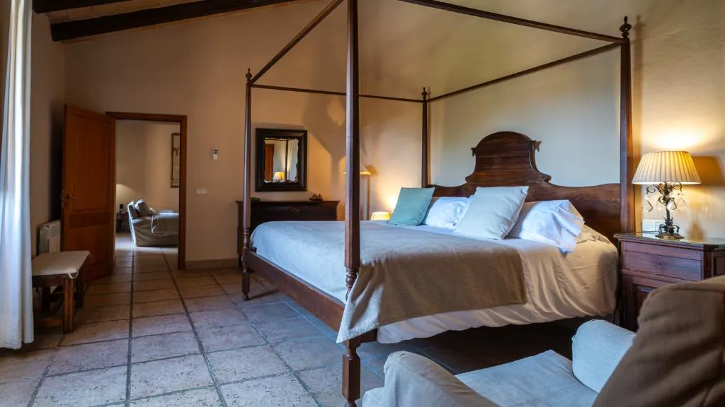 Dormitorio con cama con dosel de madera oscura y espejo antiguo, Agroturisme Son Cardaix