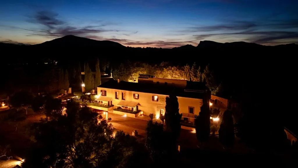 Vista nocturna de la finca señorial iluminada entre cipreses, Agroturisme Son Cardaix