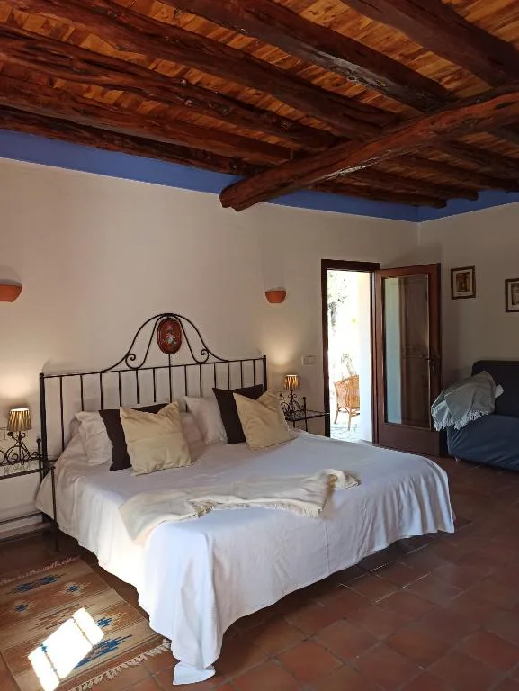 Dormitorio con cabecero de forja y techo de vigas de madera vista, Agroturismo Can Fuster