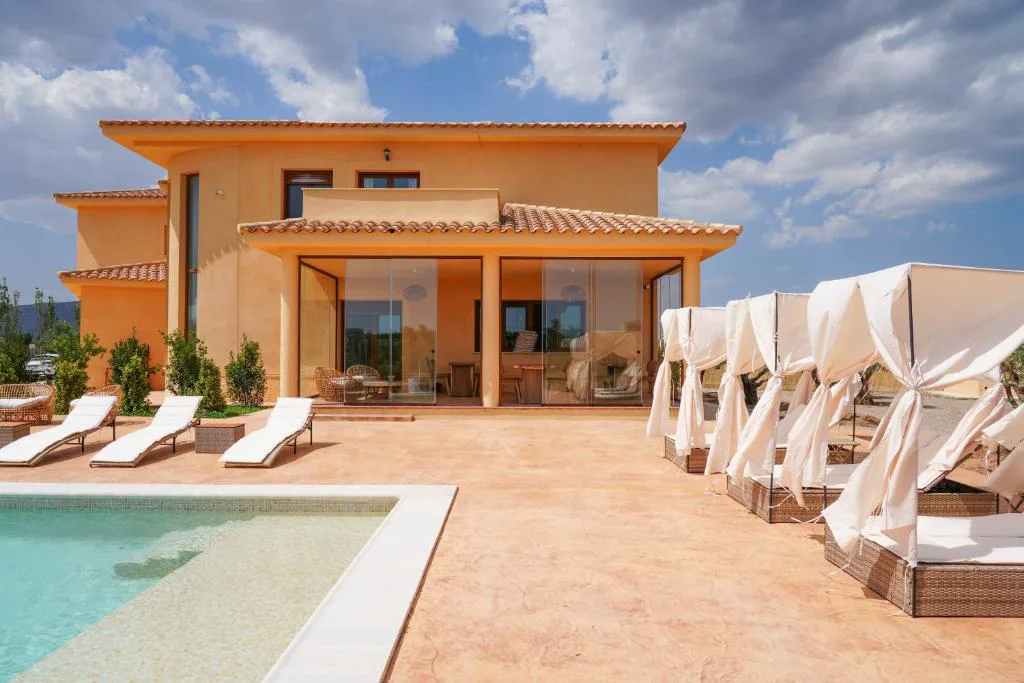 Casa anaranjada con piscina y tumbonas con dosel