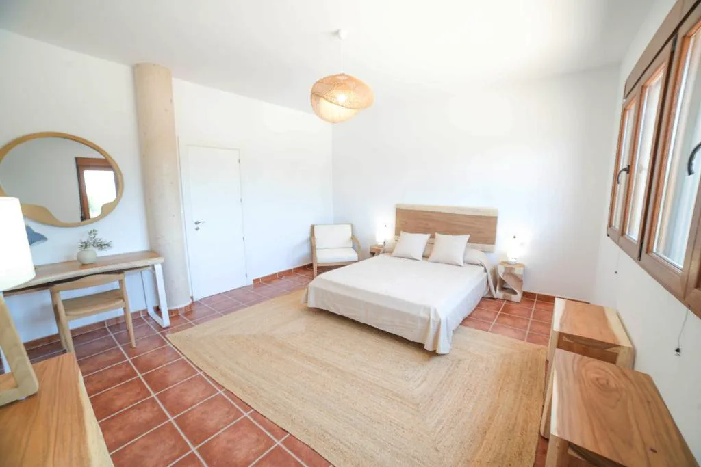 Habitación con espejo redondo y cama blanca