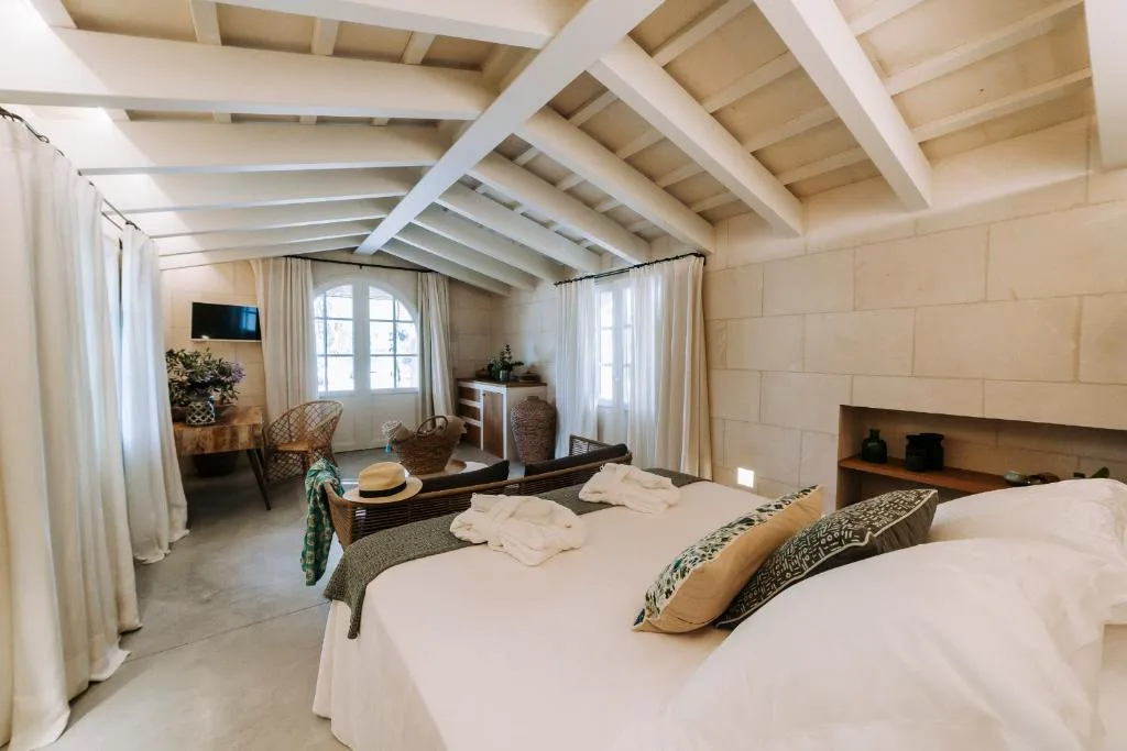 Dormitorio bajo techo de vigas de madera con sombrero de paja sobre el sofá, Agroturismo Rafal Rubí