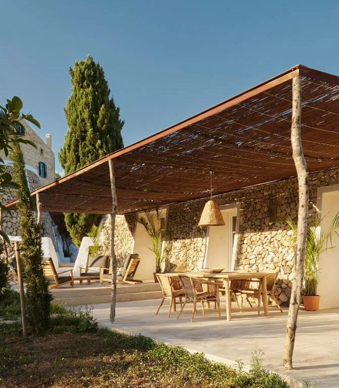 Pérgola de cañizo con mesa de comedor exterior junto al muro de piedra seca, Agroturismo Rafal Rubí