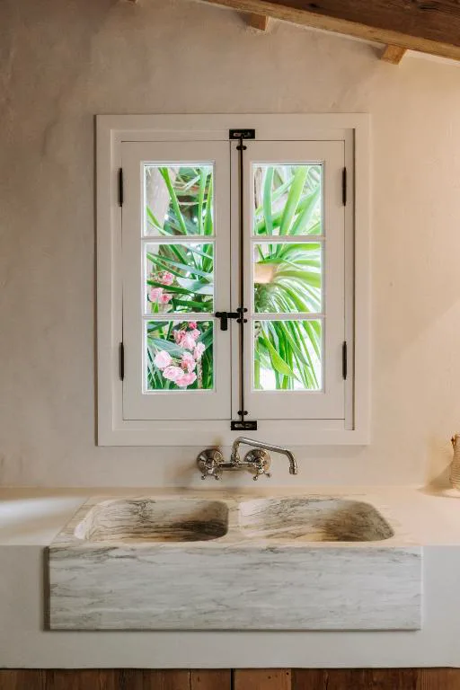 Lavabo de mármol junto a ventana con vistas al jardín, Agroturismo Rafal Rubí