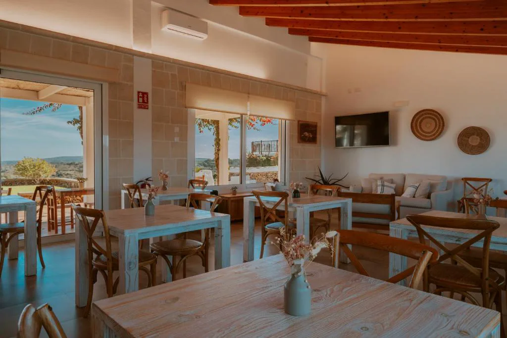 Comedor con vigas de madera y grandes ventanales abiertos al jardín, Agroturismo Son Vives