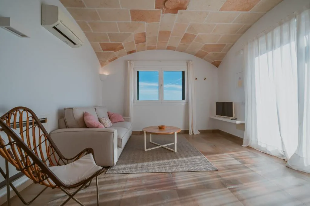 Salón con techo abovedado de piedra en tonos ocres y sofá junto a la ventana, Agroturismo Son Vives