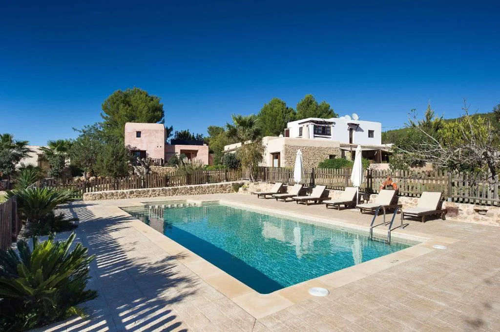 Piscina exterior rodeada de jardín y casas tradicionales ibicencas, Agroturismo Xarc, Santa Eulària des Riu