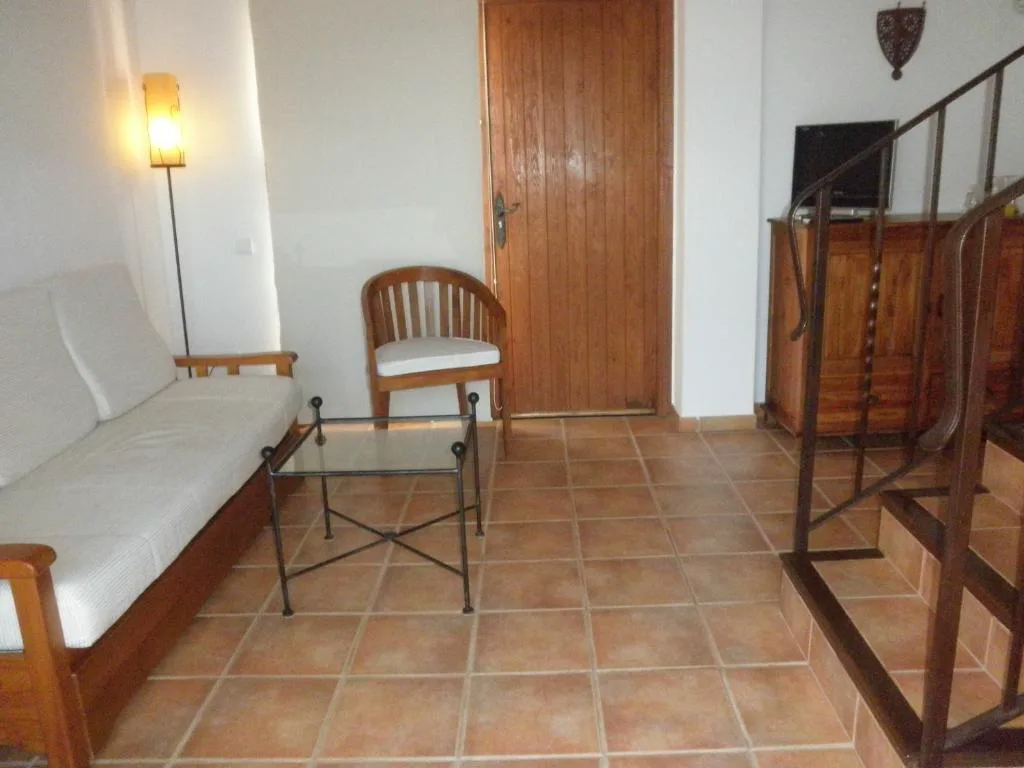 Salón con sofá y escalera de madera junto a la entrada, Agroturismo Xarc