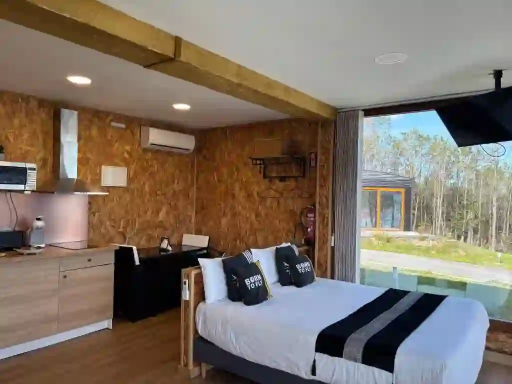 Estudio de madera con cocina abierta y cama frente al ventanal panorámico, Air Fervenza