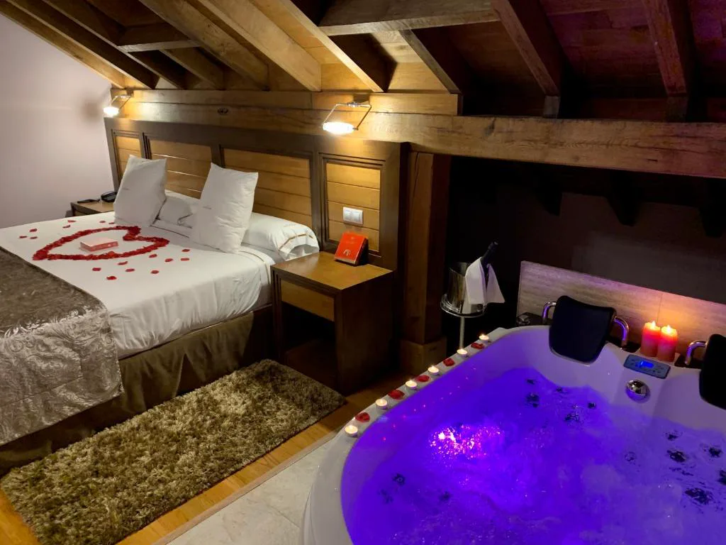Habitación de madera con jacuzzi morado y pétalos sobre la cama