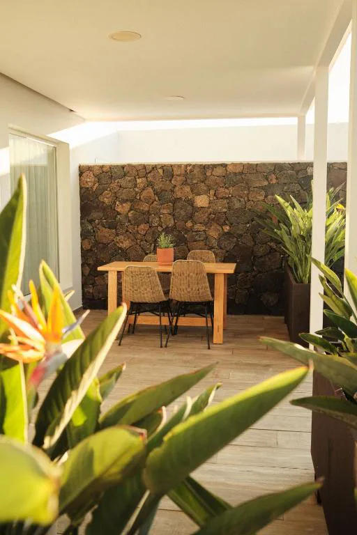 Terraza exterior con mesa de madera junto a un muro de piedra volcánica, Alava Suites