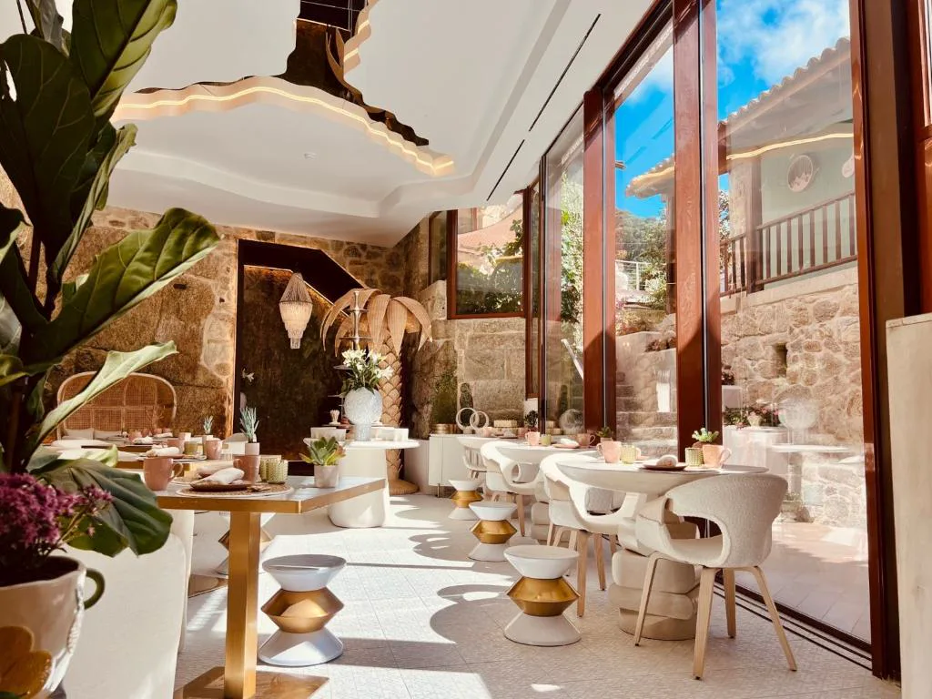 Comedor con paredes de piedra vista y grandes ventanales, Aldea Calma
