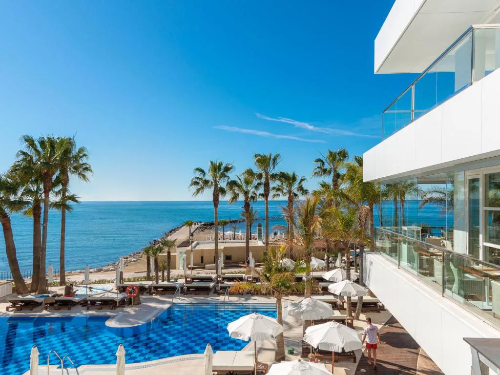 Piscina exterior con palmeras y el mar Mediterráneo al fondo
