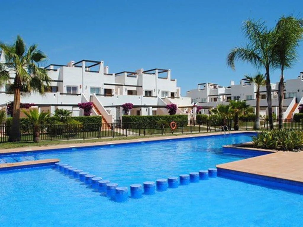 Piscina comunitaria con escalones entre bloques blancos y palmeras