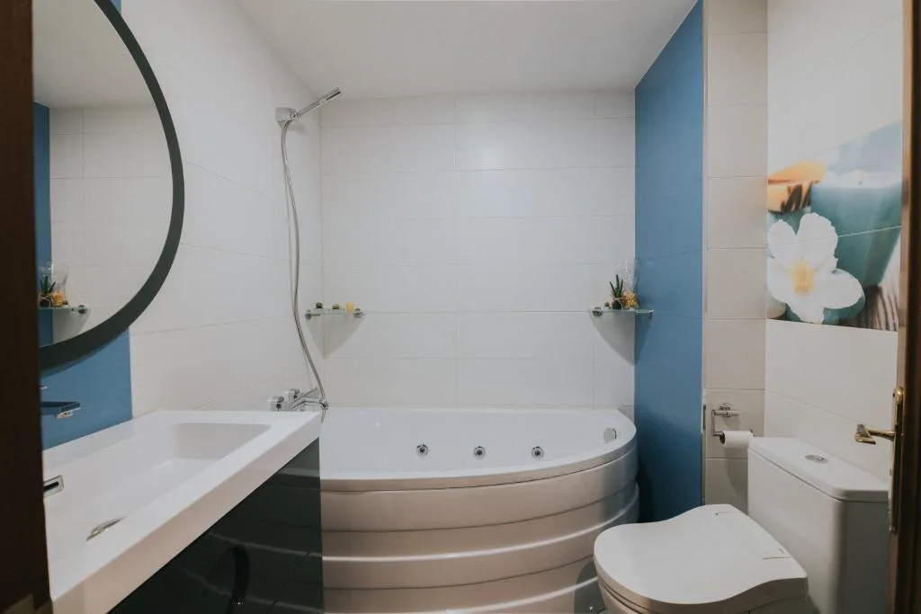Jacuzzi esquinero con chorros junto a un baño azul
