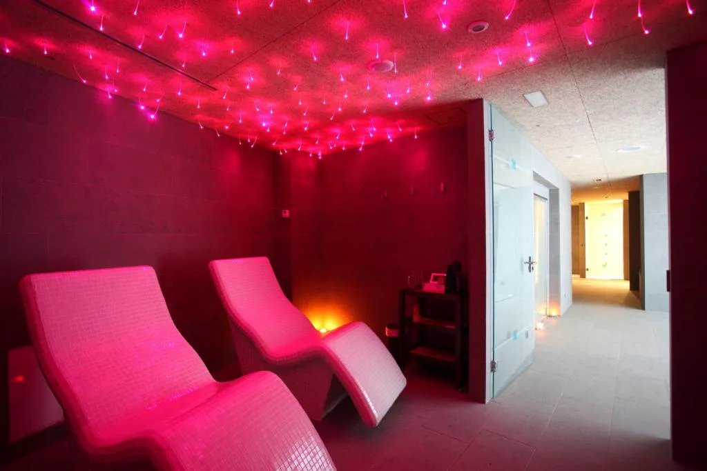 Zona de relajación del spa con tumbonas e iluminación de fibra óptica en rojo, Apartamentos Las Sirenas
