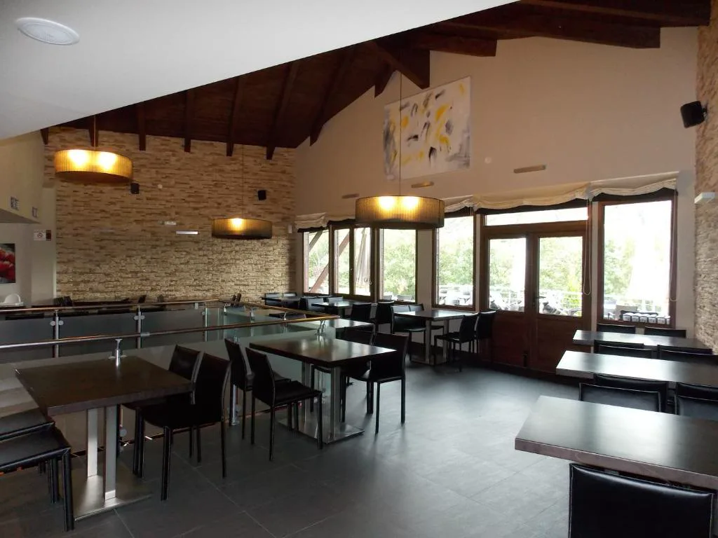 Comedor amplio con mesas negras y cocina de piedra