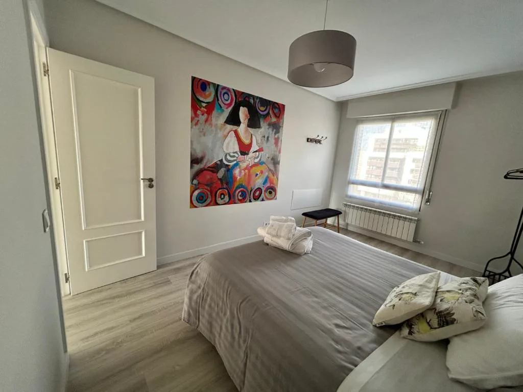 Dormitorio con cama doble y cuadro colorido
