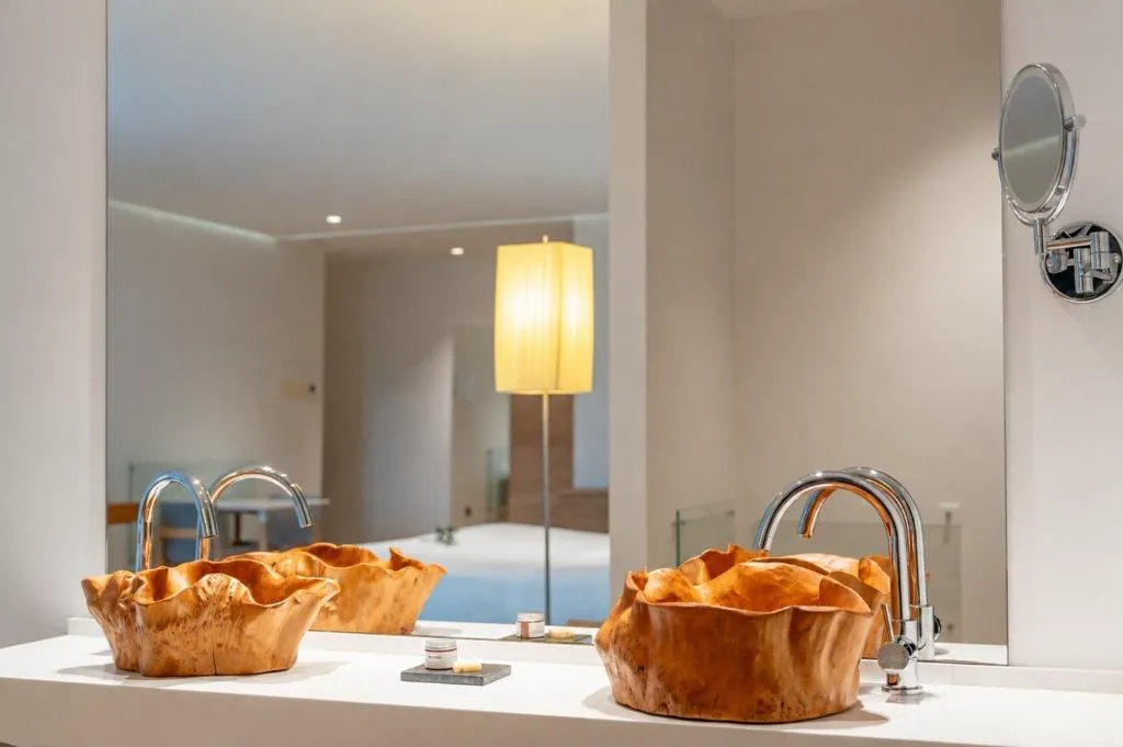 Detalle del baño con lavabos tallados en madera de raíz de estilo artesanal