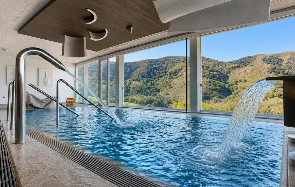 Piscina interior climatizada con vistas a las montañas del Baztán a través de un gran ventanal