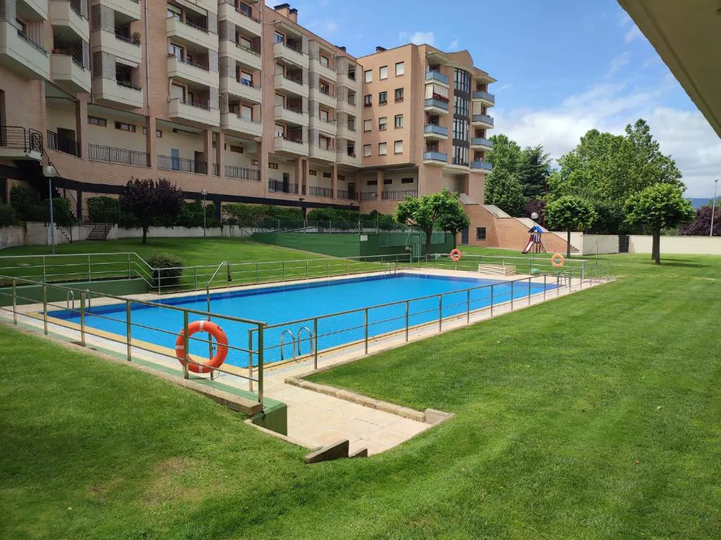 Piscina comunitaria con césped junto a bloques de apartamentos