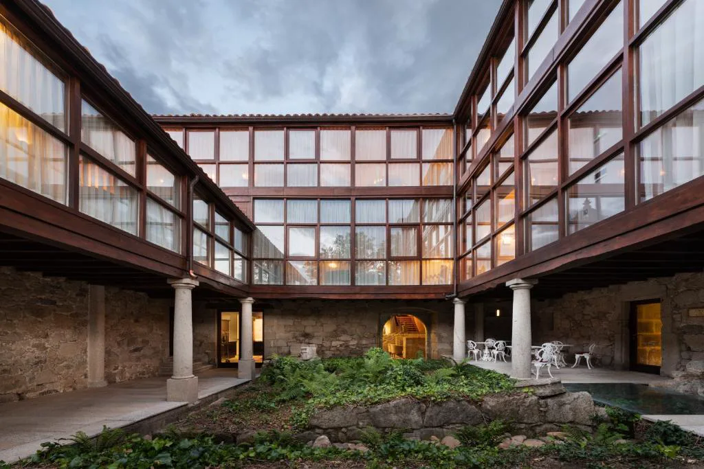 Patio interior de piedra con galería acristalada de madera, Áurea Palacio de Sober