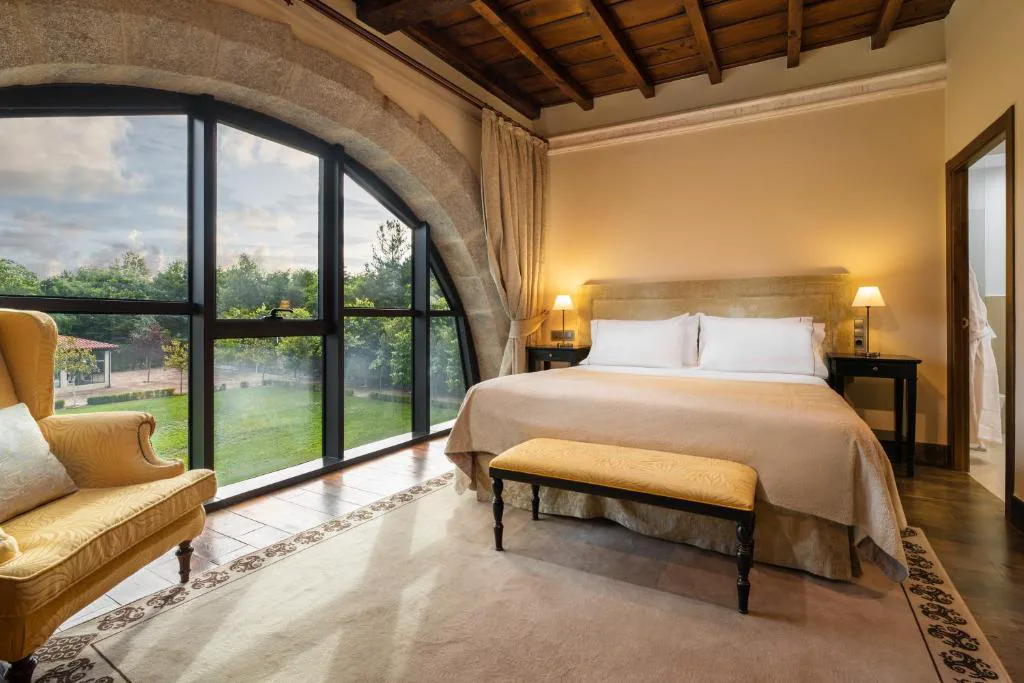 Dormitorio con techo de madera vista y ventanal en arco de piedra, Áurea Palacio de Sober