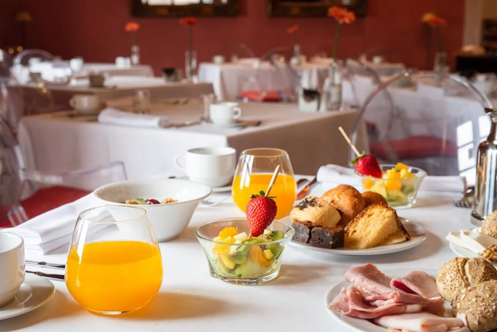 Mesa de desayuno con zumos de naranja, fruta fresca y bollería, Áurea Palacio de Sober
