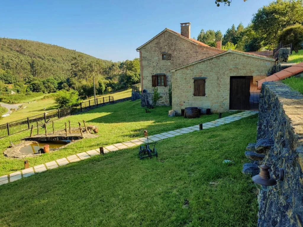 Casa de piedra tradicional con valle y montañas boscosas de fondo, A Avoa María