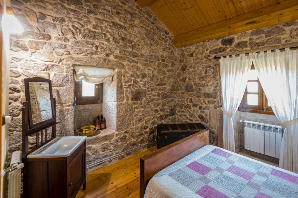 Dormitorio de piedra vista con aguamanil antiguo y baúl de madera, A Avoa María