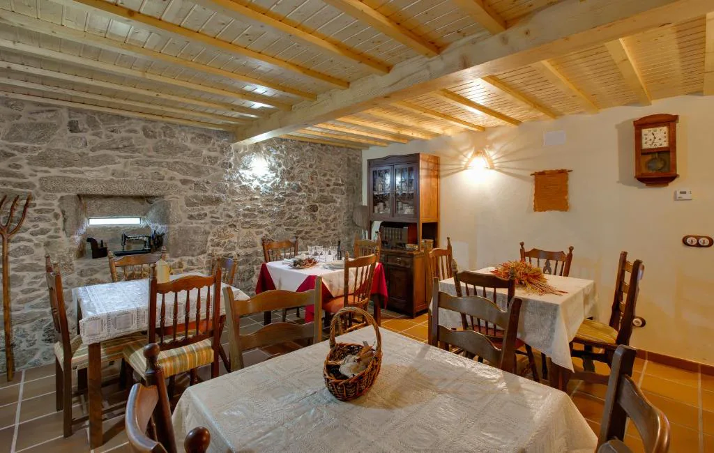 Comedor tradicional con vigas de madera, pared de piedra y reloj de pared, A Avoa María