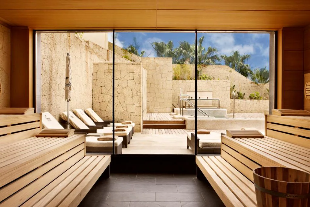 Zona de spa con tumbonas junto a piscina en terraza de madera, Bahia del Duque