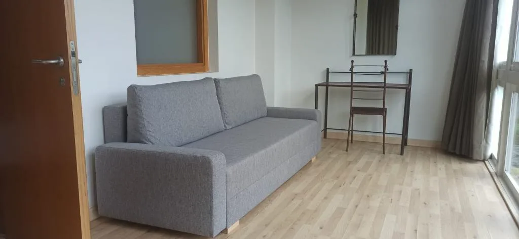 Salón con sofá y suelo de madera clara, Balneario Acuña