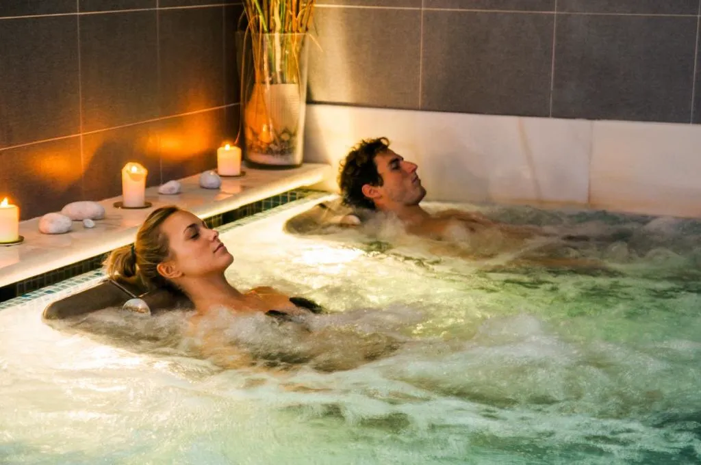Pareja relajándose en la bañera de hidromasoterapia con velas, circuito termal del balneario