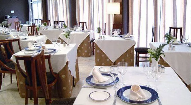 Comedor con mesas vestidas de blanco y vajilla azul, BALNEARIO ARNOIA