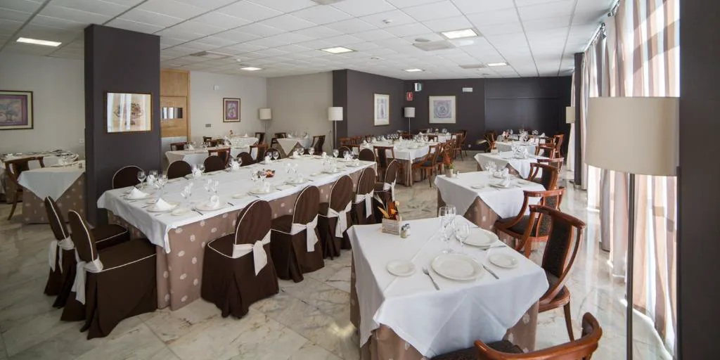 Salón comedor con mesas vestidas y sillas tapizadas en marrón, BALNEARIO ARNOIA