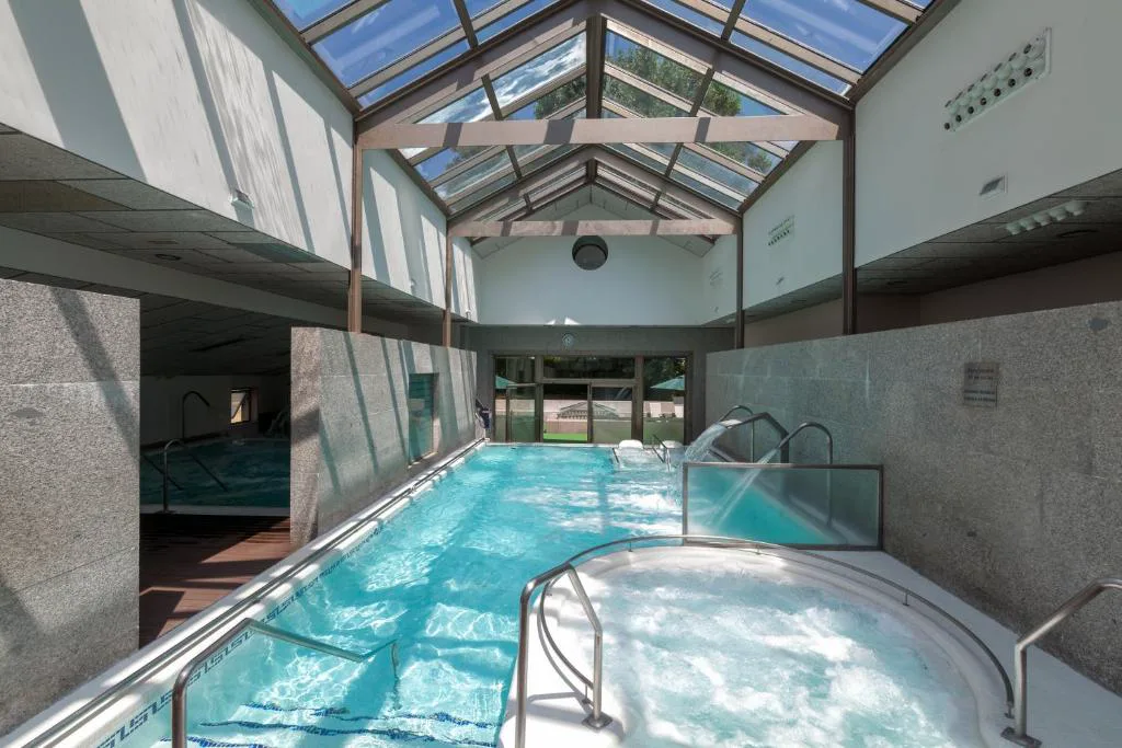 Piscina interior acristalada con jacuzzi circular bajo techo de cristal, Hotel Balneario de Compostela, Brión
