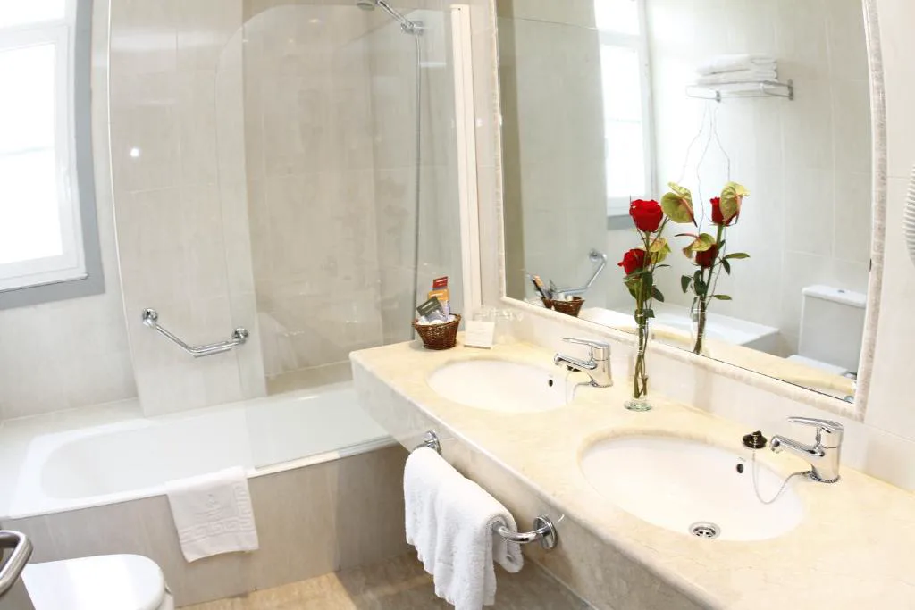 Baño con bañera, ducha y rosas rojas sobre el lavabo, Balneario de Mondariz