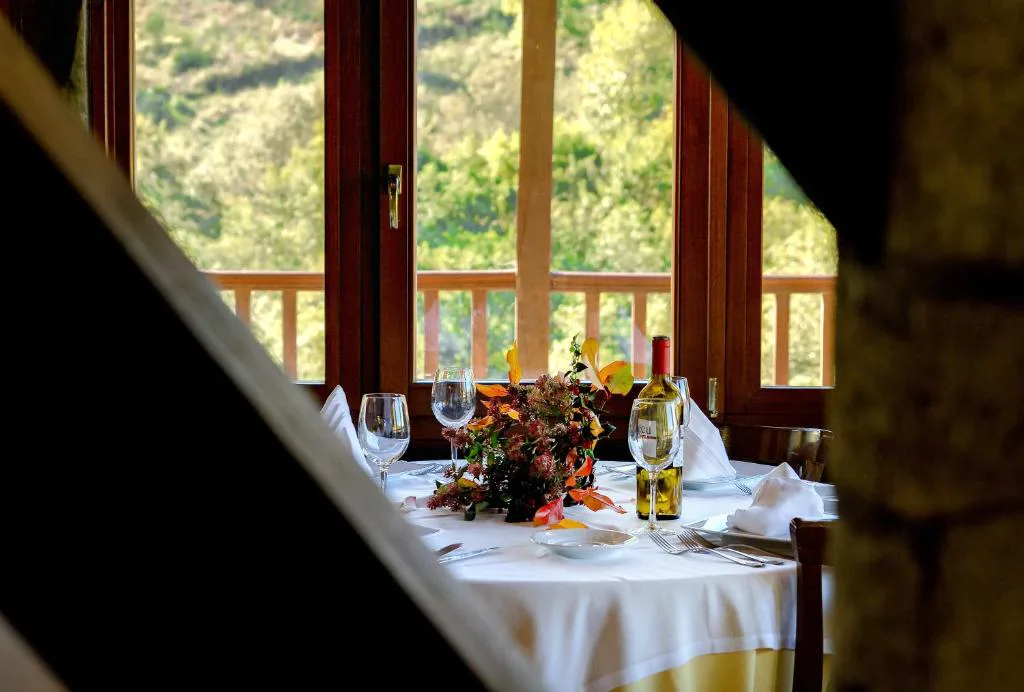 Restaurante con mesa puesta y grandes ventanales al bosque, Hotel Balneario Río Pambre