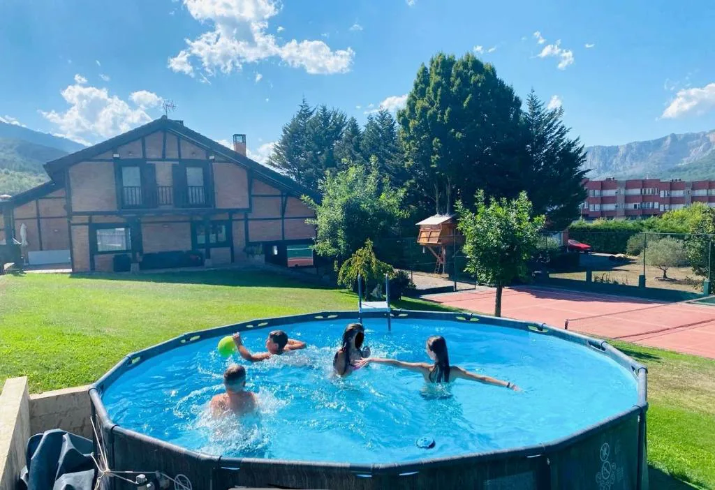 Piscina redonda con bañistas y el chalet detrás