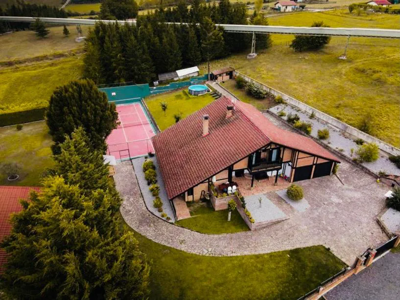 Vista aérea del chalet con pista de tenis y piscina