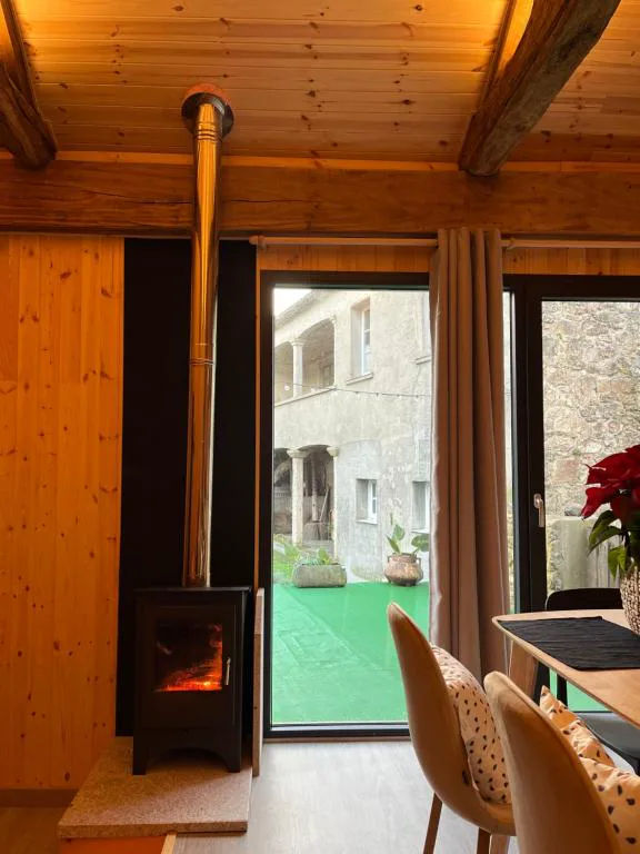 Chimenea de leña encendida junto a ventanal con vistas al patio de piedra, Bella Casa Araujo