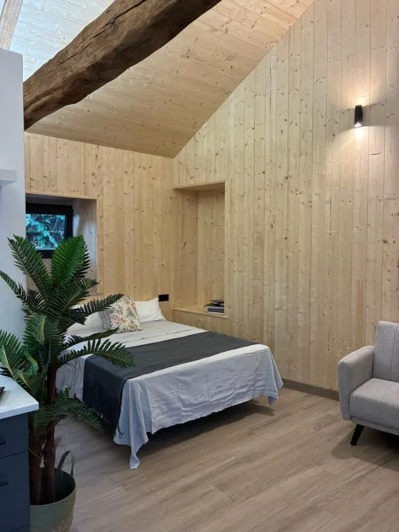 Dormitorio abuhardillado con viga de madera vista y sillón junto a la cama, Bella Casa Araujo